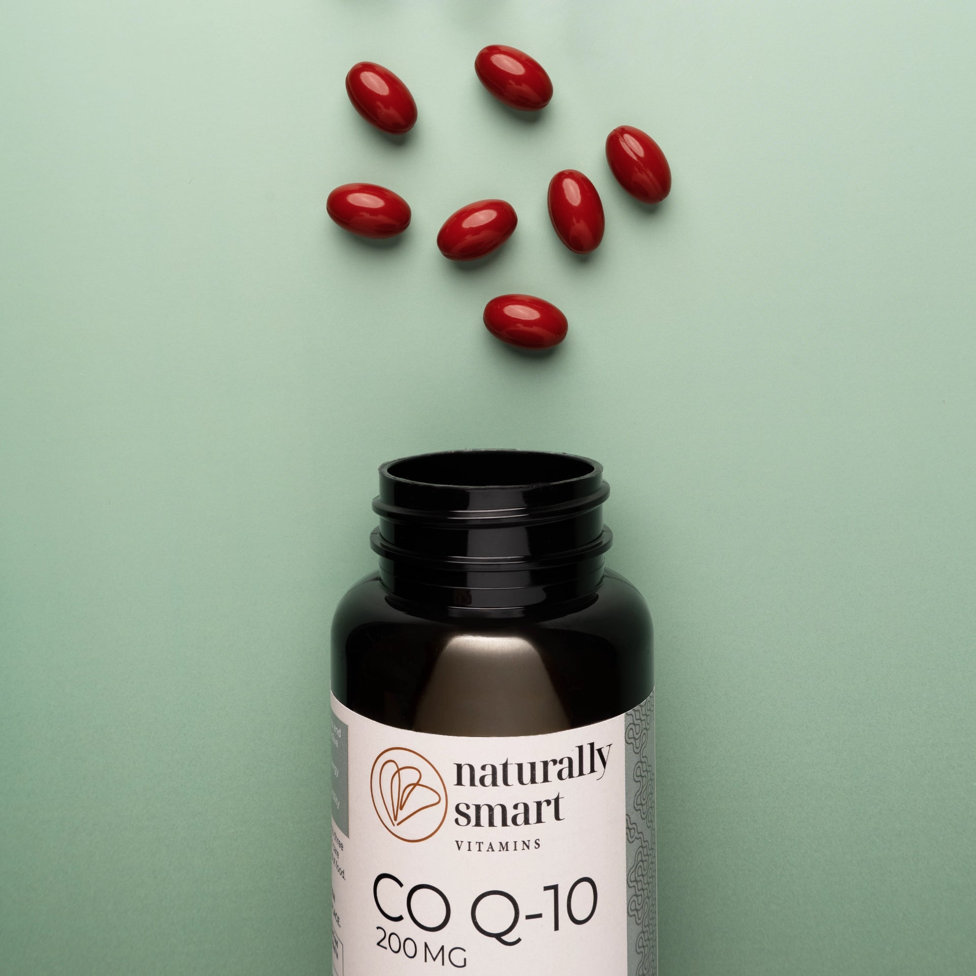 Co Q10 bottle with red capsules on a green background