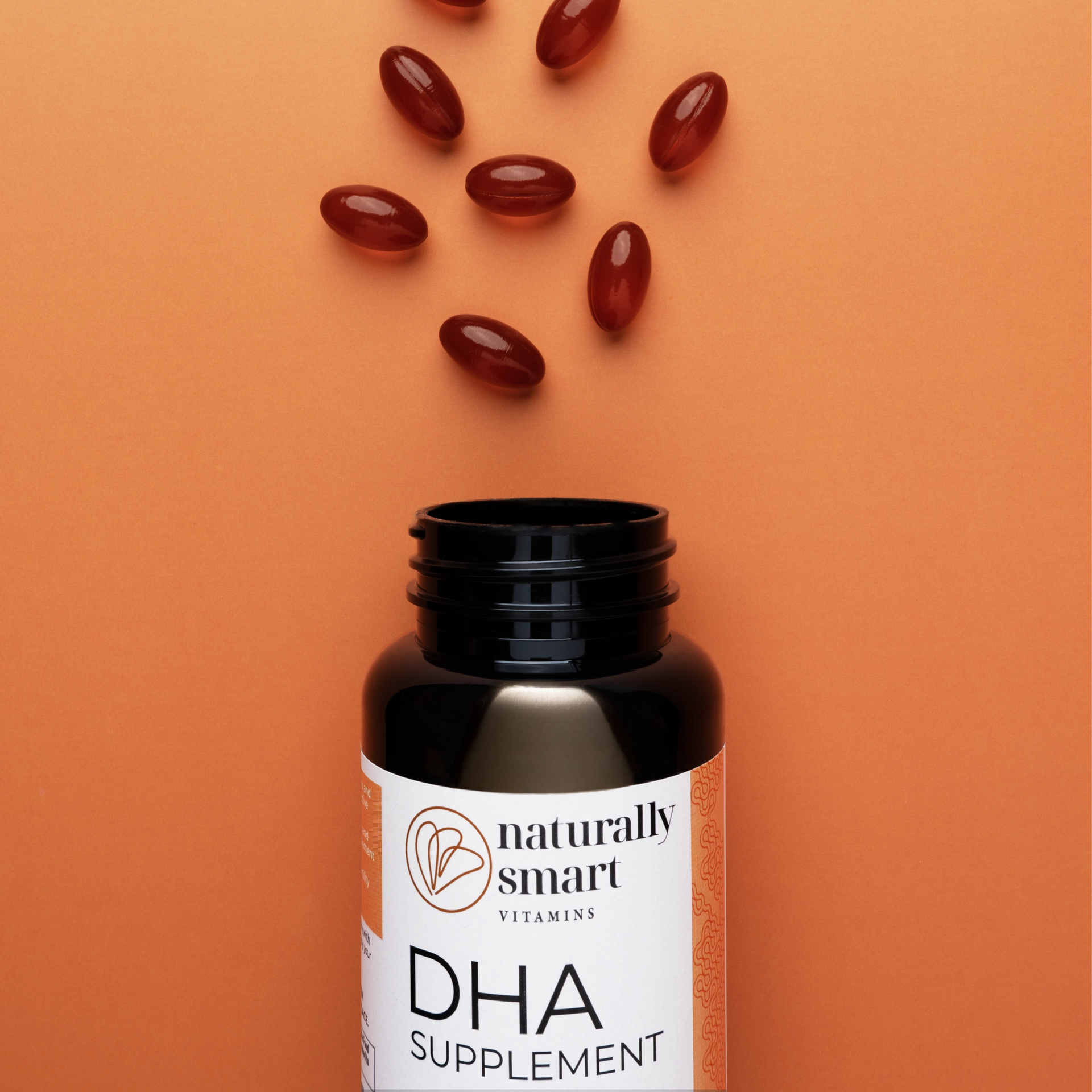 DHA supplement bottle with softgels on an orange background