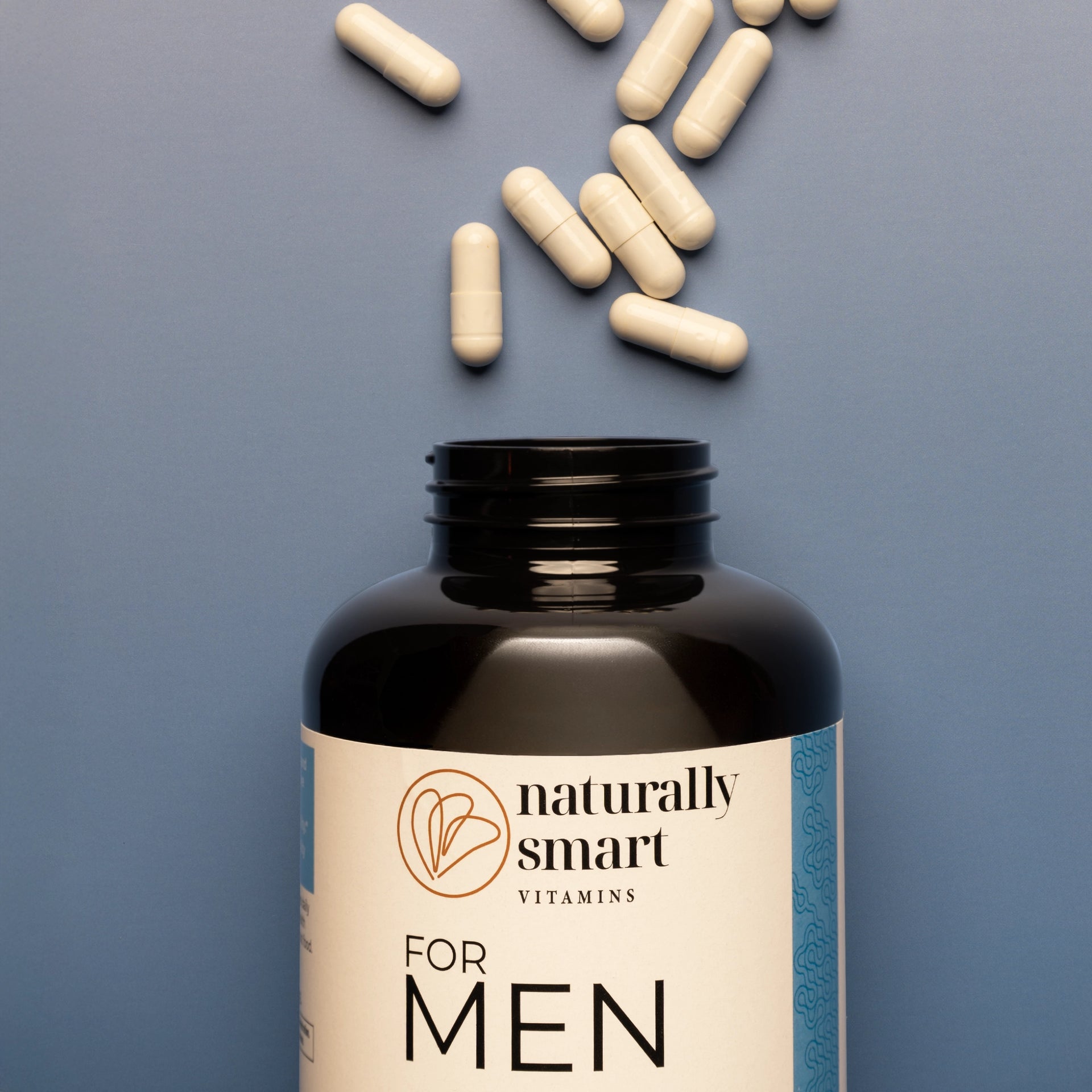 For Men Vitamin bottle with scattered capsules on a blue gray background