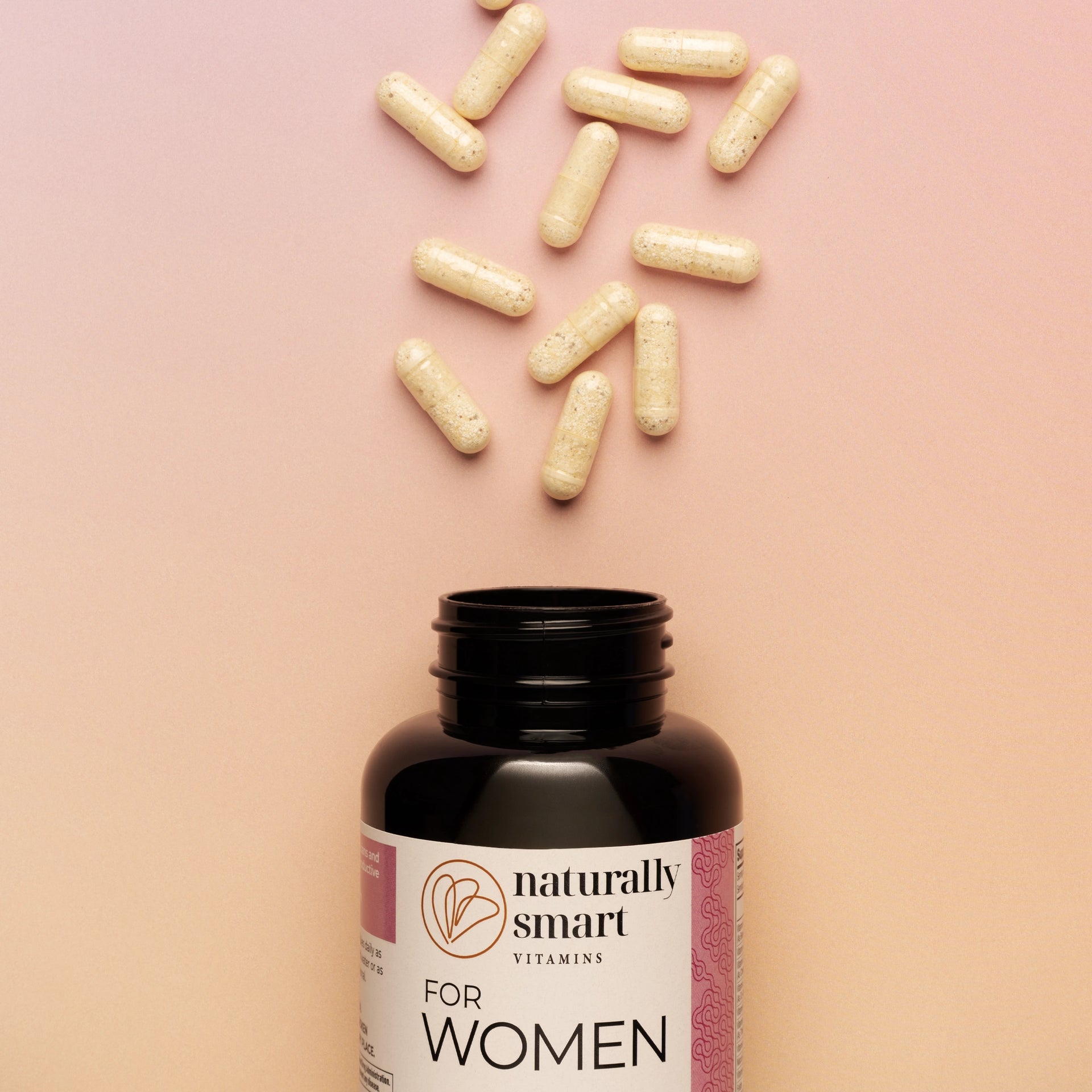 For Women vitamin bottle with scattered capsules on a pink background